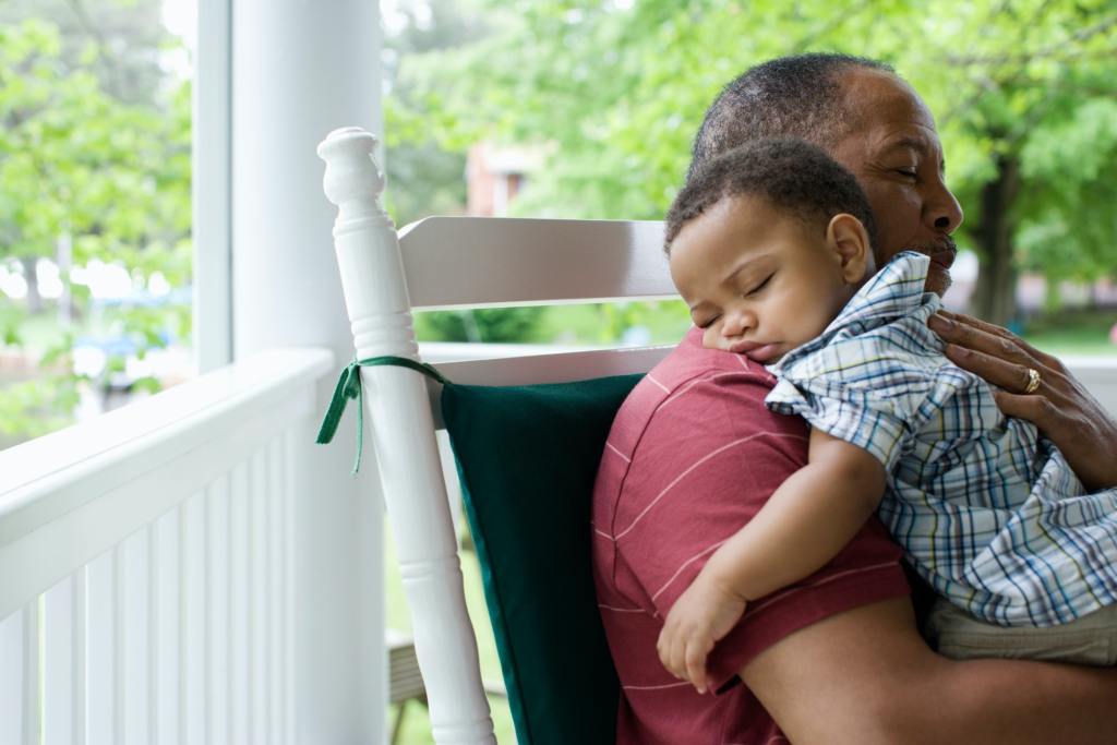 A grandfather holding his sleeping grandson.