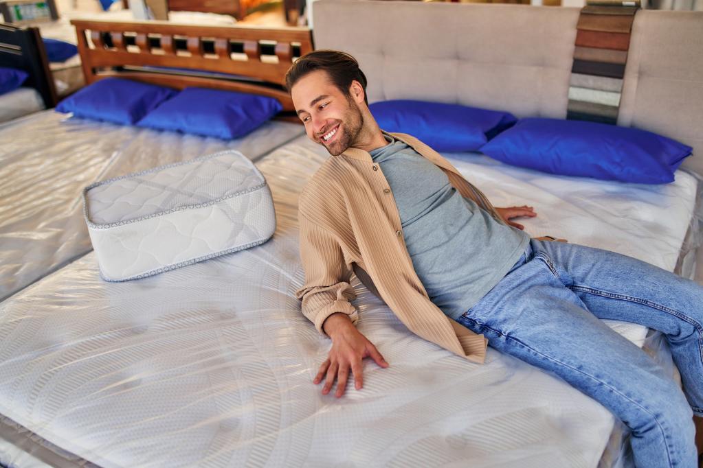 Beds, mattresses, and pillows store. Man choosing the right mattress size.