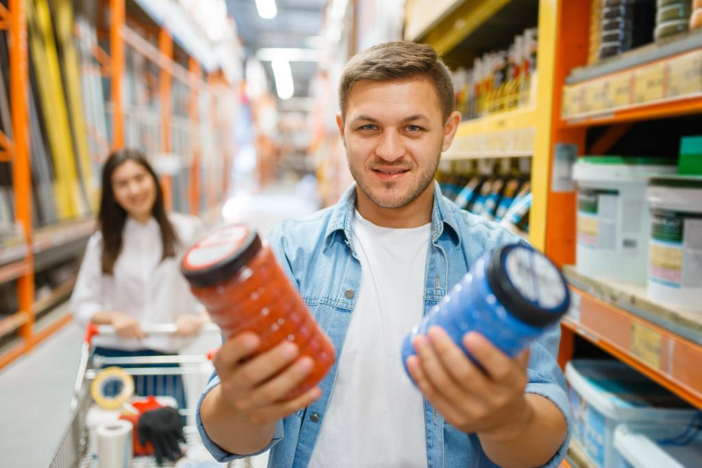 Couple with a cart buying paints in hardware store.