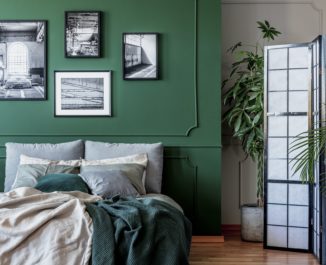 Gallery of black and white posters and photos on emerald green wall in trendy bedroom