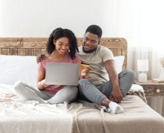 Couple sitting in their new bed.