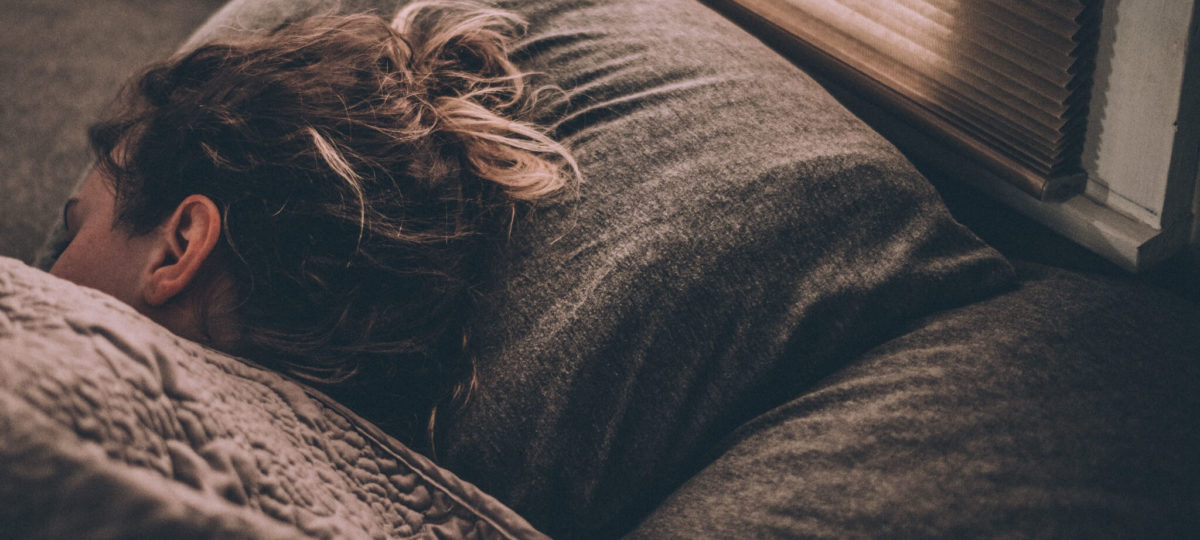 Woman sleeping on her side under covers in bed