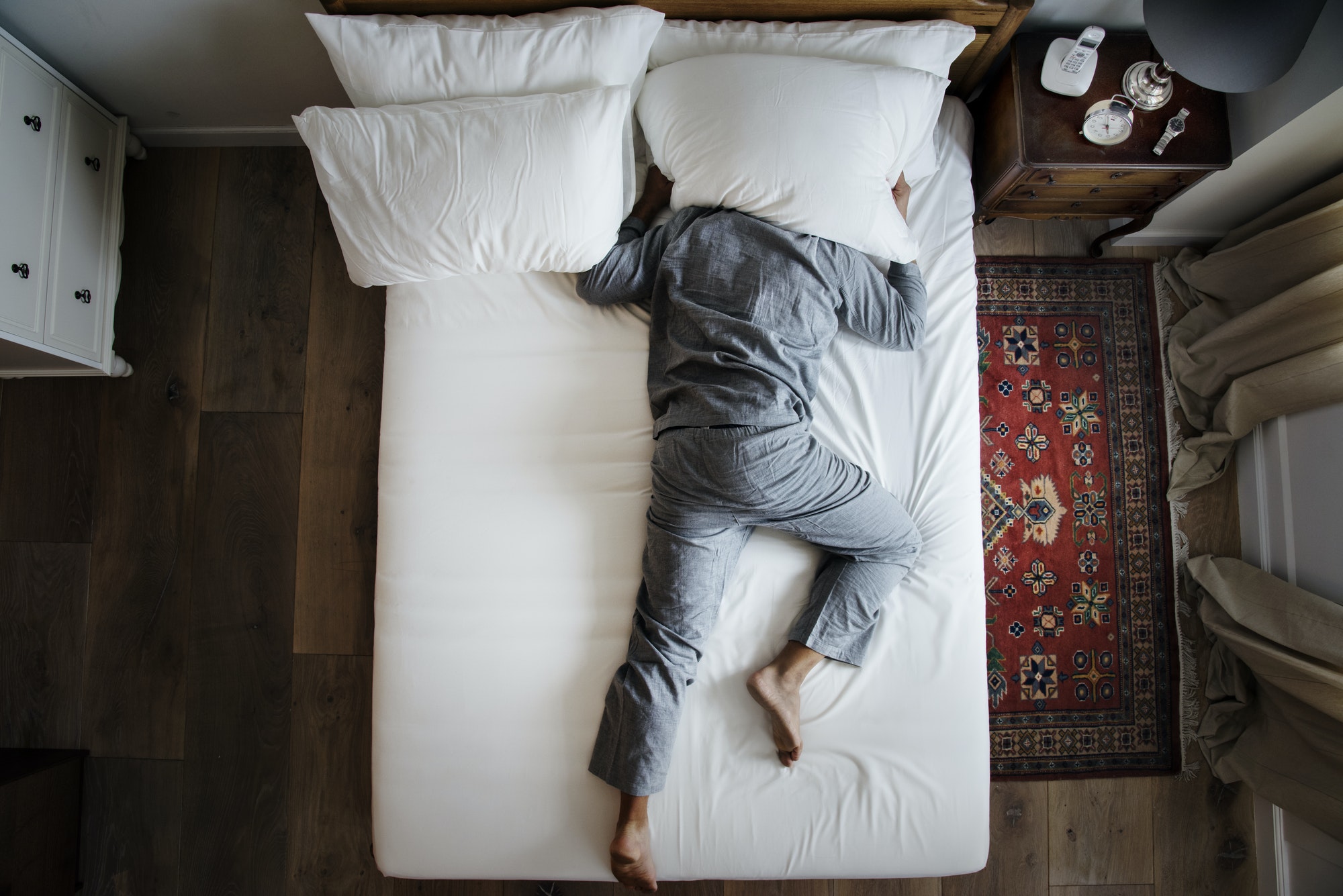 Man in bed not being able to sleep because he isn't taking melatonin supplements for sleep. 