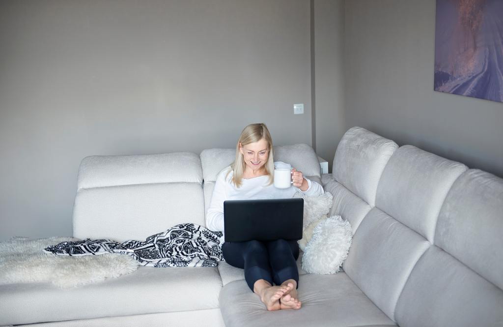 Woman using laptop on sofa at home.