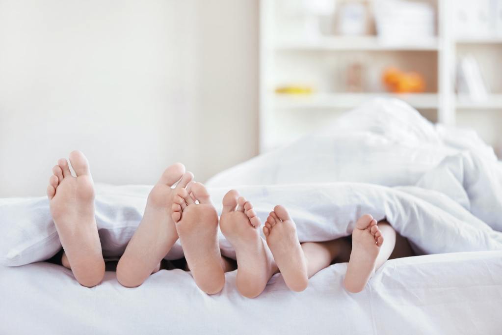 Feet sticking out of the bottom of a blanket in bed.