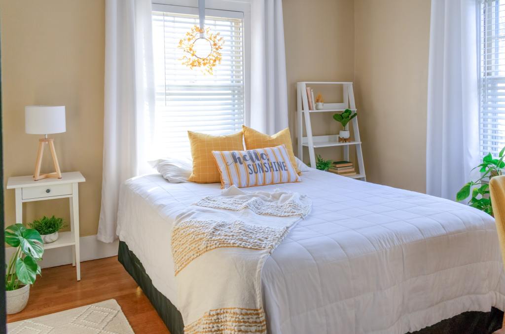 Stylish small bedroom decorated in yellow and white.