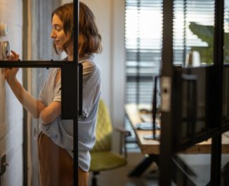 Woman controlling temperature with a thermostat at home