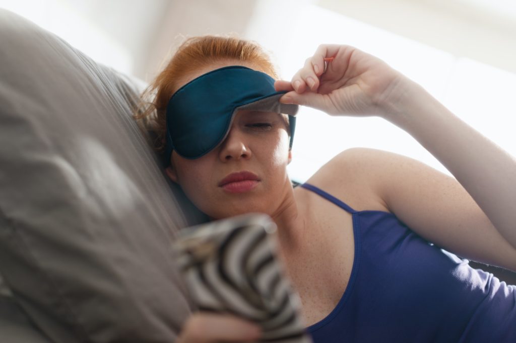 Woman In Bed Waking Up Snoozing Alarm Clock on her Mobile Phone.