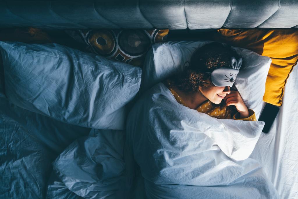 Woman sleeping with a sleep mask on her eyes. Key factors for good sleep.